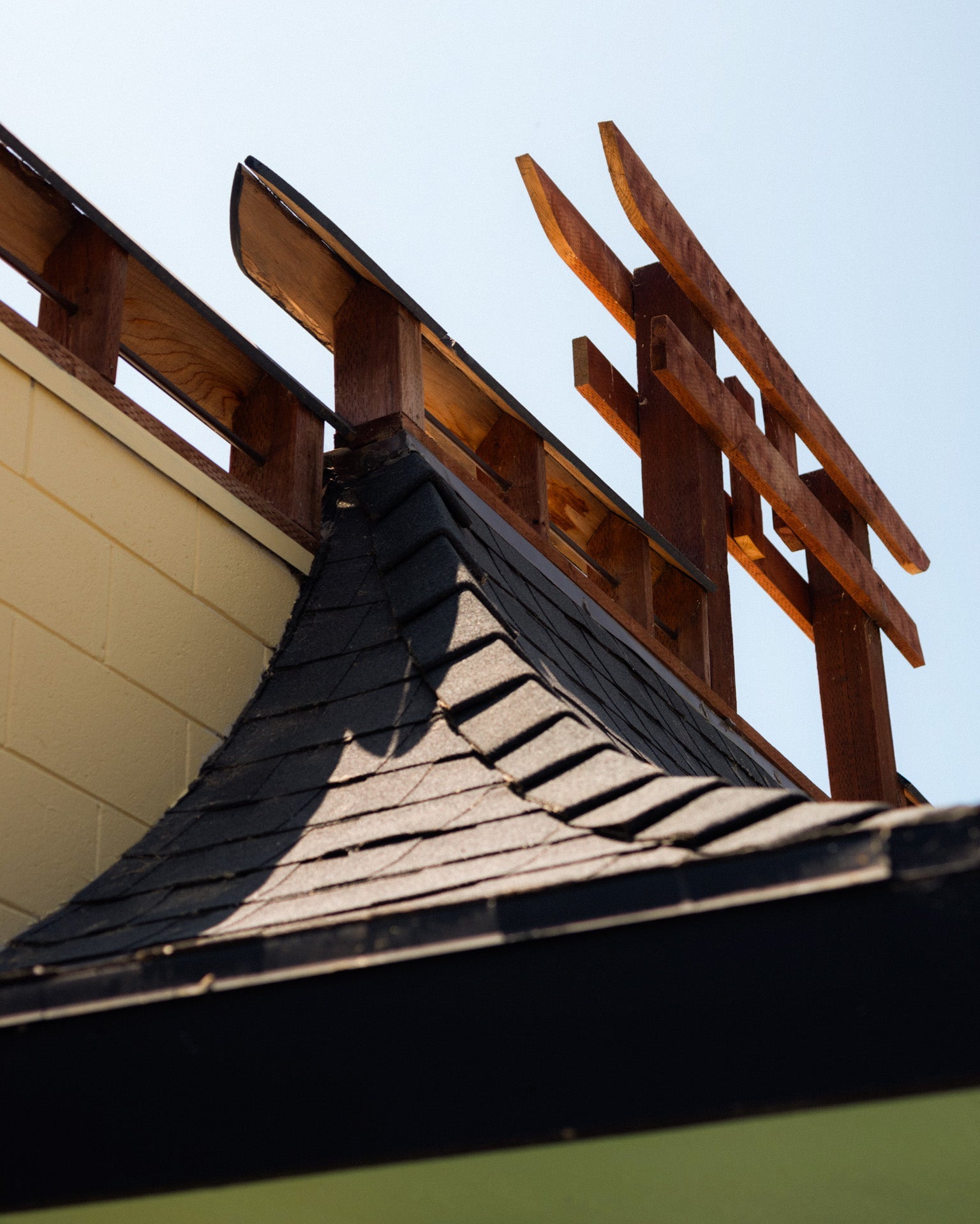 Damaged roof with missing shingles and a wooden ladder leaning against it.