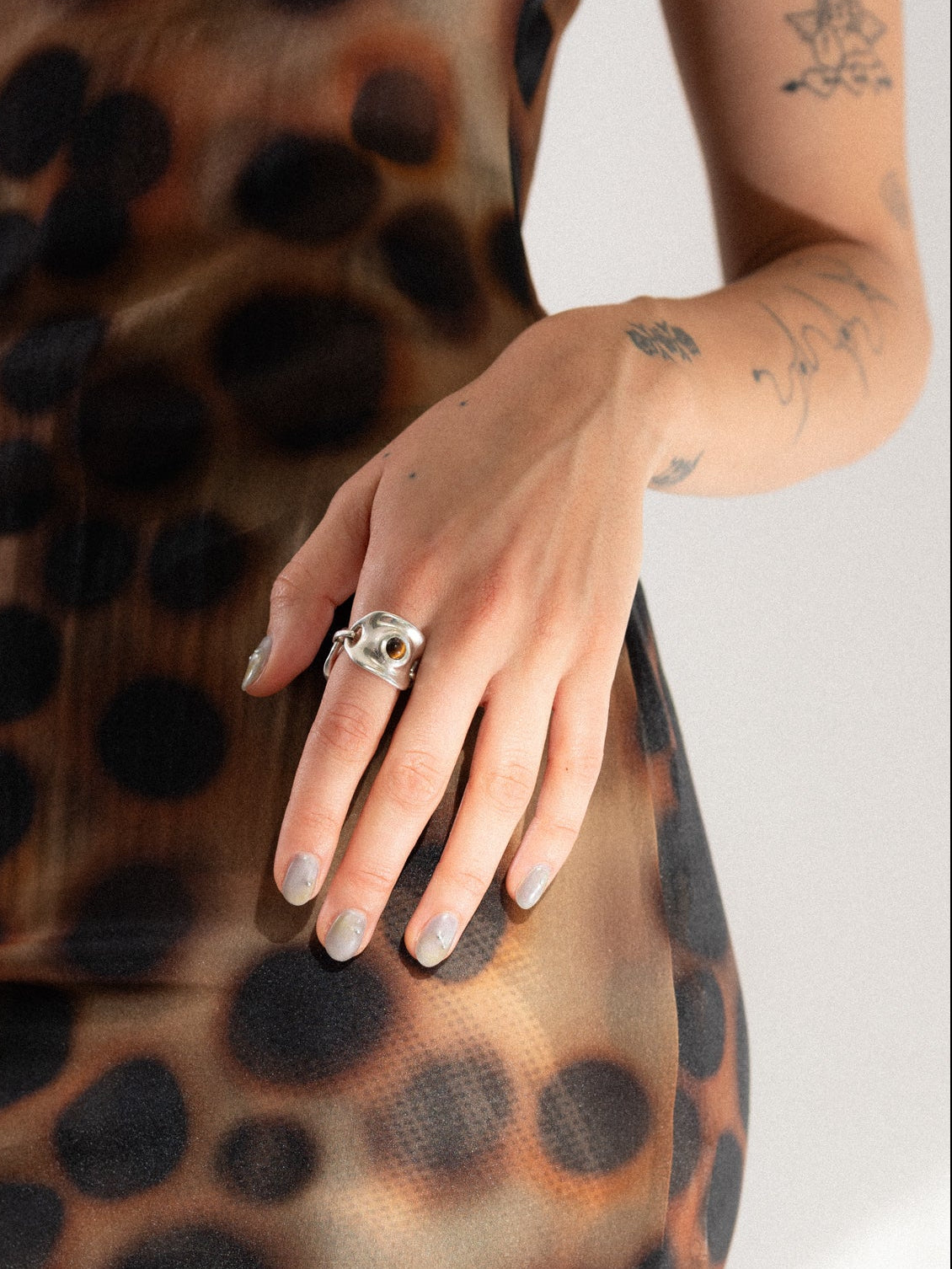 Person wearing a leopard print dress with a close-up of a hand and ring.